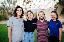 four students and interns hugging and smiling at the camera