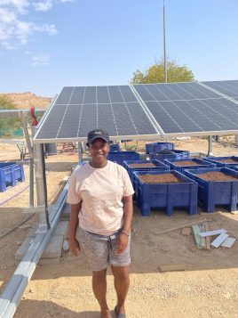 Roselyne Kamau in front of solar panels
